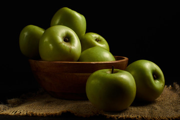 Green apples Simirenko in wooden bowl at black background. 