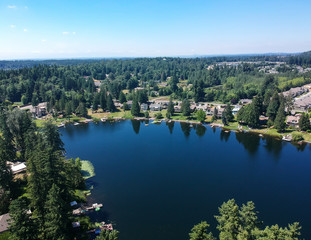 Tranquil Shady Lake on a bright clear day in summertime with trees reflecting in the water a blue sky and white clouds with lily pads dockside in Renton King County Washington State