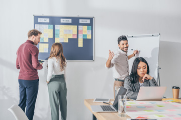 mixed race man with outstretched hands near asian businesswoman and scrum masters