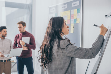 selective focus of attractive asian scrum master writing on flipchart