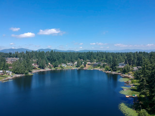 Tranquil Shady Lake on a bright clear day in summertime with trees reflecting in the water a blue sky and white clouds with lily pads dockside in Renton King County Washington State