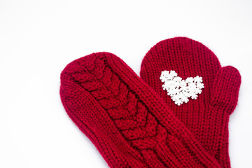Close up of a knitted red mitten with white snowflakes in the shape of a heart on a white background, isolated. Сoncept of Christmas, winter, love, care and Valentine's day