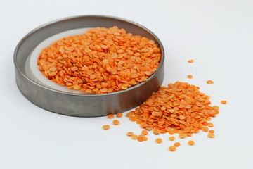 Uncooked red lentils scattered on white surface