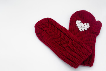 A knitted red mitten with white snowflakes in the shape of a heart on a white background, isolated. Сoncept of Christmas, winter, love, care and Valentine's day. Copy space
