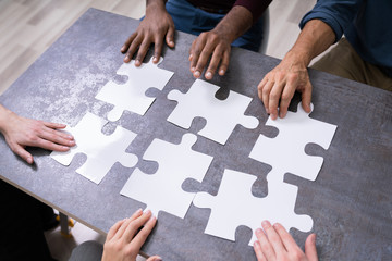 High Angle View Of Businesspeople Solving Jigsaw Puzzle