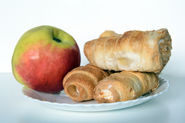 On an white plate are an apple and cream cakes. Concept - diet, health, food choice,