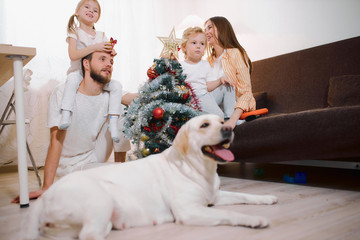 Happy caucasian family have new year's bustle at home, decorating new year tree with colorful...