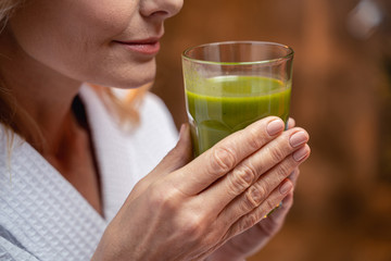 Hands clutching a glass of green smoothie