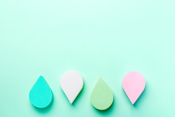 Beauty, make up sponges or beauty blenders in pastel colors on aqua menthe color background, copy space, top view. Beauty treatment, self care background overhead