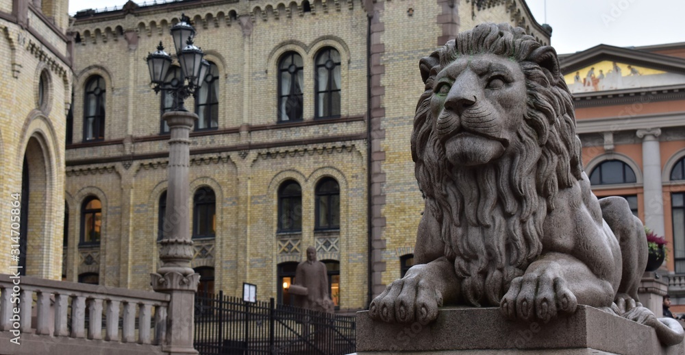 Wall mural detail lion statue in front of parliament of norway back ground with yellow building