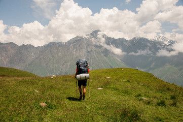Fototapeta na wymiar Hiker with backpack walks among hills and mountains