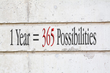 Inspirational quote : 1 Year = 365 Possibilities written on concrete wall background