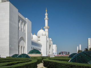 bright white Sheikh Zayed Grand Mosque with golden domes against the blue sky on a sunny day, Abu...