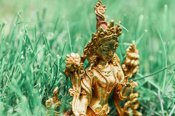 Figure of a female Buddhist deity (Green Tara) sitting on a lawn 