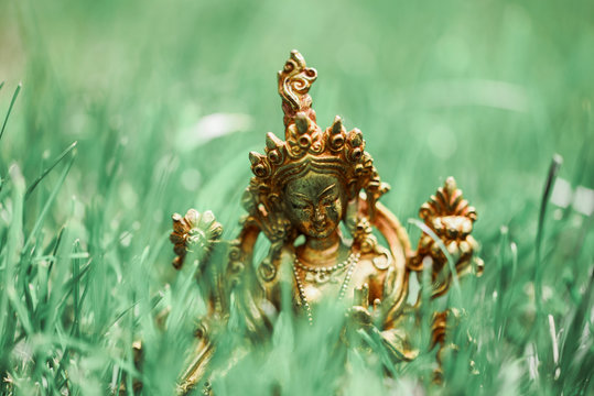 Figure of a female Buddhist deity (Green Tara) sitting on a lawn 