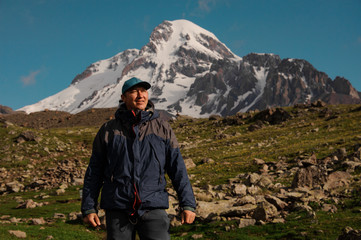 Naklejka na ściany i meble Smiling traveller posing in front of mountain