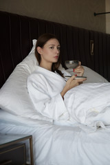 Serene woman drinking coffee in the bed, casual relaxing time alone