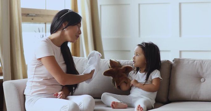 Cute asian child girl wear crown playing puppets with mother