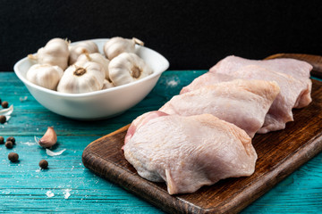 Raw chicken thighs on blue wooden background.