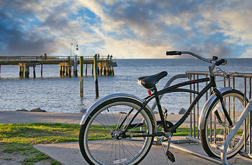 A lone bicycle in rack in front of pier at the beach