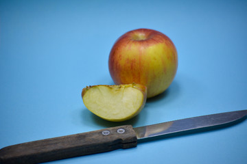 Fresh apple and slice with knife on blue background