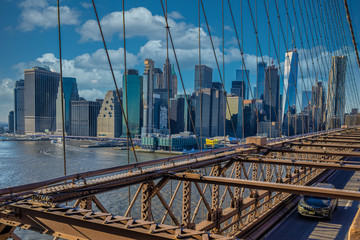 New York skyline from Brooklyn Bridge with clouds in sky in background