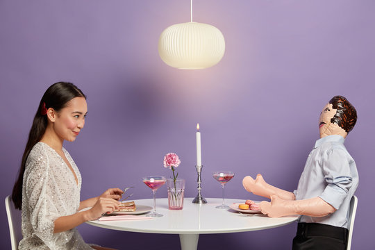 Photo of Asian woman has talk with unreal boyfriend, pretends having romantic dinner with gentleman, tries to find love in real life and start relationship, spends time in company of layman doll