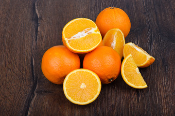 Oranges, whole and slices, on a wooden table.