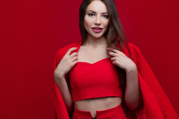 Stylish young woman in a red suit on a red background.