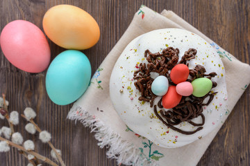 Easter cake next to colored eggs and branches of willow twig