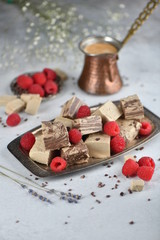 Oriental sweets, halva slices on a metal dish, decorated with raspberries, with Turkish coffee. Background, vertical.