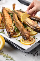 Whole fish, fried or smoked, on a baking sheet with lemon and herbs.
