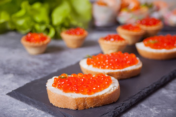Fresh red caviar on bread on the black plate. Sandwiches with red caviar.