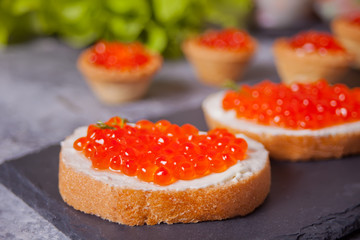 Fresh red caviar on bread on the black plate. Sandwiches with red caviar. Delicatessen. Gourmet food.