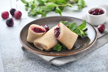 thin pancakes rolled up with a nickel of cherry on a plate with a beautiful background