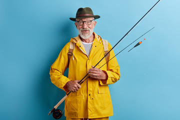 senior man preparing float to go fishing, close up photo. isolated yellow background, studio shot