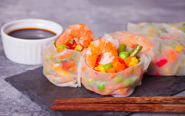 Spring rolls with vegetables and shrimps in rice paper on the black plate