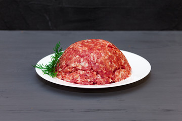 Plate with fresh raw ground beef. Sprig of dill