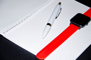Gray notebook for writing on black background. Ballpoint pen. Smart watch with a red strap. Flat Lai, copies of the paste. View from different sides. Smartphone. Businessmen set kit white background.