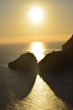 Luz del sol al atardecer pasando entre las rocas de la isla como un eclipse