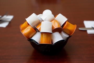 A view from the side of a bowl of non-dairy creamer on a table in a restaurant setting.