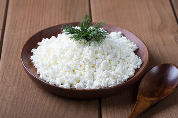 Cottage cheese in a wooden plate on a wooden table