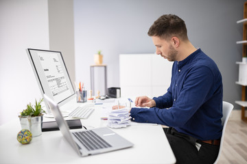 Businessman Calculating Invoice In Office