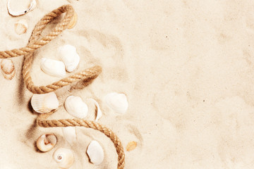 Fototapeta na wymiar Rope and shells on the sand, travel summer background