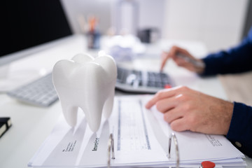 White Tooth In Front Of Man Calculating Bill