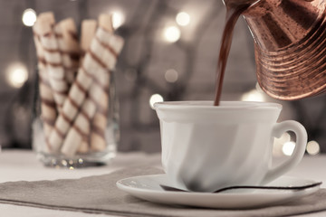 On the table is a cup of fresh aromatic coffee with sweet tubes