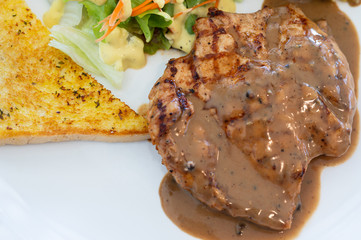 Top view grilled pork steak set in white dish on wooden table background.pork grill, french fries, bread and salad.Restaurant menu.