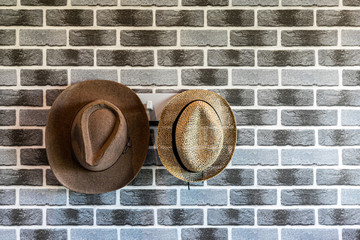 A hat hung on a brick wall