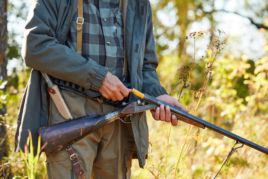 Man holding shotgun loading it. Forest background. Hunting, people concept