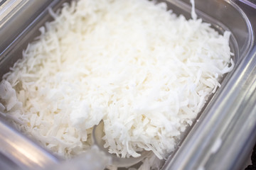 A closeup view of a container full of shredded coconut on display at a local dessert shop.